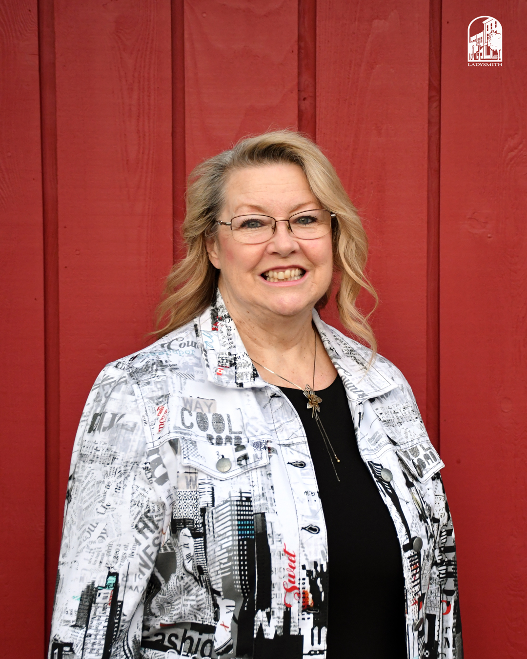 Deena Beeston smiling in front of a red wooden wall